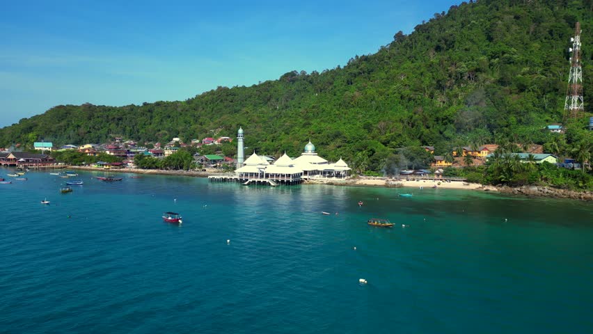 Islamic white mosque at beach on Perhentian Island. Majestic aerial top view flight wide orbit overview drone
4k