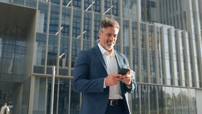 Indian or latin confident middle age male entrepreneur businessman holding mobile cell phone for work. Confident mature hispanic senior business man using smartphone cellphone app at office building - Powered by Shutterstock - Get 15% off with code: PIKWIZARD15