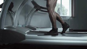Closeup of male feet in sneakers training and walking on incline treadmill view on sportsman exercising and jogging on running machine at gym