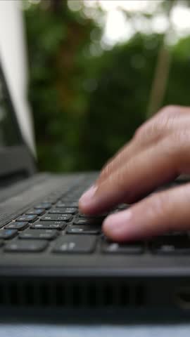 A close-up shot of someone typing on a laptop keyboard outdoors. Home office day. A notebook keyboard. A dirty laptop keyboard. A dusty computer keyboard. Close-up shot of a man typing on a computer.
