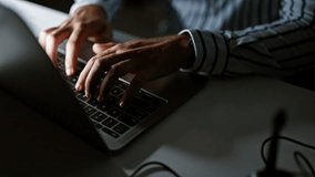 Close-up of a man's hands typing on a laptop keyboard in a dark office setting, depicting work and technology - Powered by Shutterstock - Get 15% off with code: PIKWIZARD15