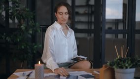 A female astrologer takes a tarot card from the table and reads what is written on the back while sitting at her desk in her office. The woman smiles while looking at the camera. Close-up - Powered by Shutterstock - Get 15% off with code: PIKWIZARD15