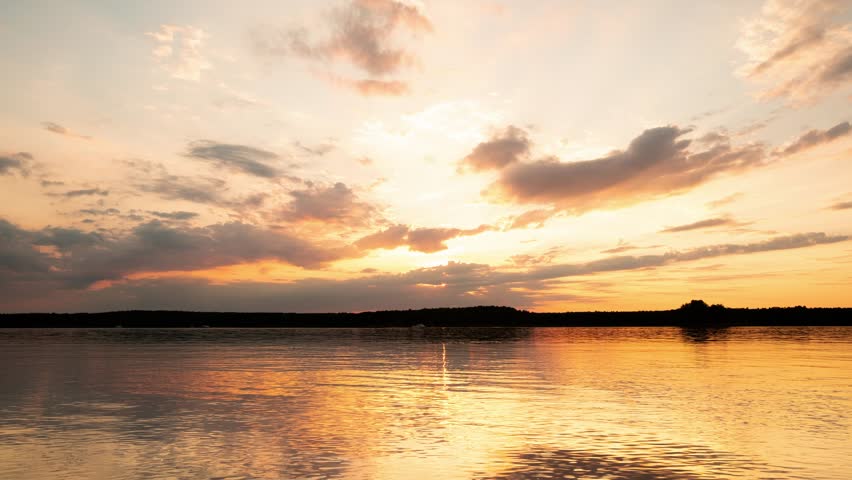 Sky and clouds at sunset over the lake shore. Beautiful, dramatic cloudy skyline in the red, orange and blue colors over the lake. Stock footage time lapse video 4k