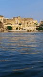 Udaipur City Palace on the bank of lake Pichola - Rajput architecture of Mewar dynasty rulers of Rajasthan. Tourist boat is heading to the side. Udaipur, India