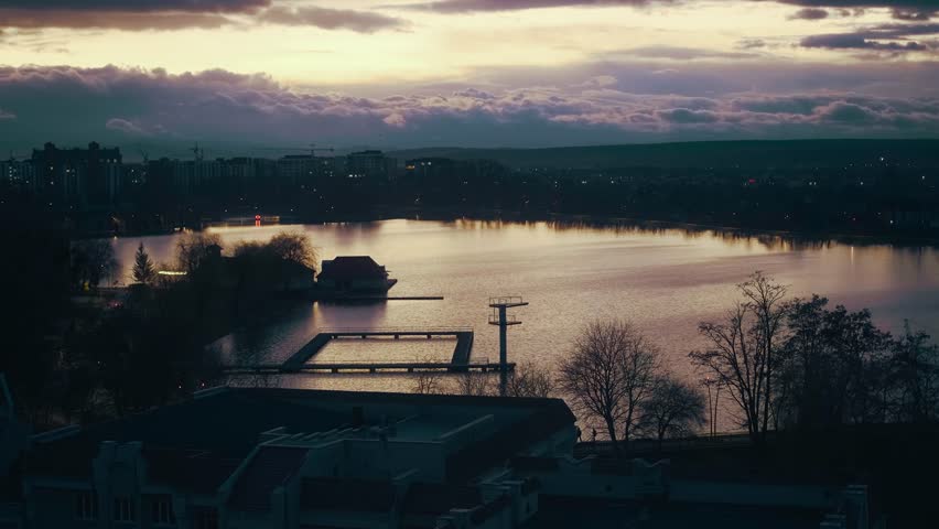 City lake on sunset. Aerial view of city landscape. Sundown over the city park and pond