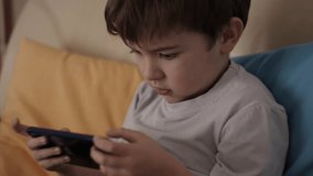 Little Boy Gamer Playing Video Game on Mobile Phone. Child Happy Playing Games With Phone. Preschooler Kid Plays Video Game On Smartphone. Harm for Mental Kid Health Eyesight Gambling Addiction. - Powered by Shutterstock - Get 15% off with code: PIKWIZARD15