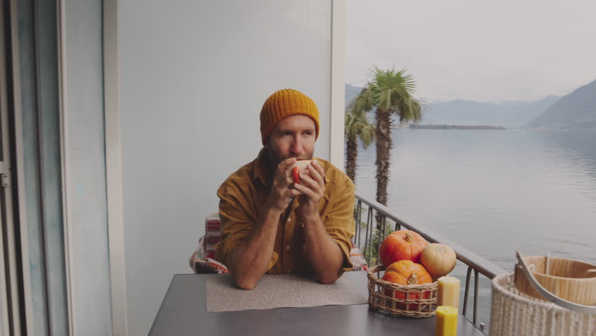 Man relaxing at home on his balcony by the lake with a cup of tea