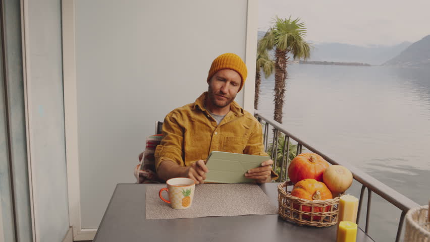 Man relaxing at home on his balcony by the lake with a cup of tea