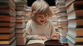 Handsome little child flips through the book pages in library. Elementary school boy enjoying reading in bookshop or bookstore - Powered by Shutterstock - Get 15% off with code: PIKWIZARD15