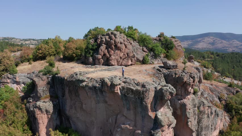 Aerial View Of Male Traveler Walking On Steep Rocky Plateau At Harman Kaya Thracian Sanctuary In Bulgaria.