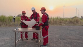 Engineer team standing looking down blueprint on the table to meeting planing project install wind turbines in agricultural sugarcane plantation area, in the morning sunlight background, 4k video