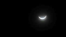 waning solar eclipse time lapse movement video of moving solar crescent shape across black dark sky 