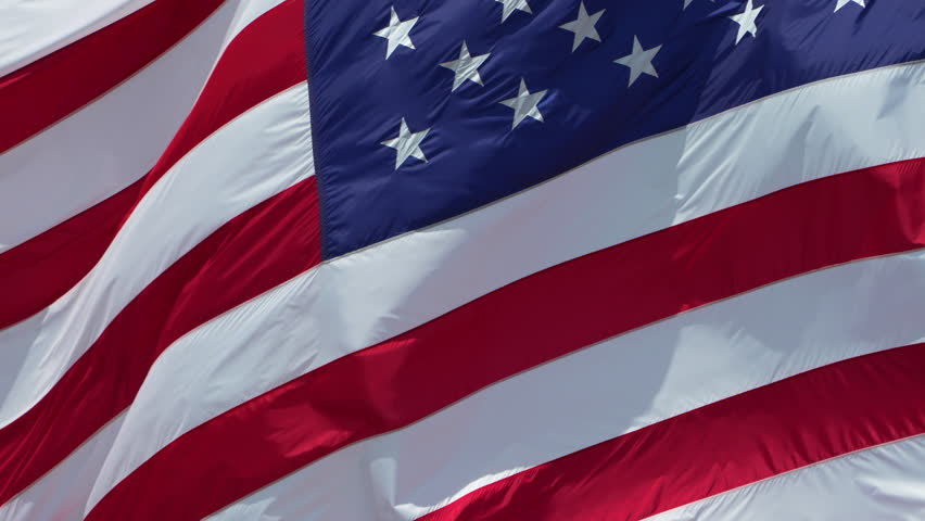 USA national flag waving on wind against blue sky. American stars and stripes spangled banner as symbol of democracy