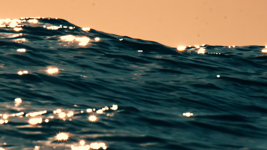 Huge waves roll in the open ocean at sunrise