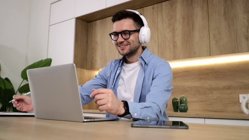 A male student enrolled in an online course uses headphones and a tablet to participate in an online educational session on the school's video chat platform.
 Royalty-Free Stock Footage #3482745313