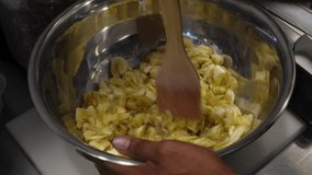 Close-up of a man preparing banana puree with a wooden spatula in a metal plate for banana bread. High quality 4k footage