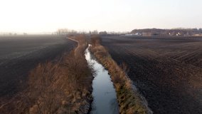 Aerial view of reed filled canal, in the sunset during winter. Flying above land