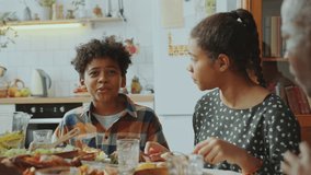 Little African American brother and sister chatting and laughing over meal when having fun on holiday dinner with family at home - Powered by Shutterstock - Get 15% off with code: PIKWIZARD15