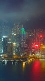 Aerial timelapse of illuminated Hong Kong skyline cityscape downtown skyscrapers over Victoria Harbour in the evening. Hong Kong, China. Zoom out effect