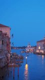 View of Venice Grand Canal with boats and Santa Maria della Salute church in the evening from Ponte dell'Accademia bridge. Venice, Italy
