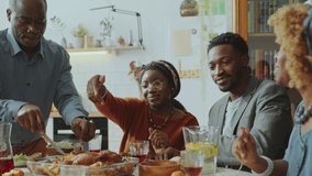 African American grandfather serving roasted chicken on plates for family members gathered for holiday dinner at home - Powered by Shutterstock - Get 15% off with code: PIKWIZARD15