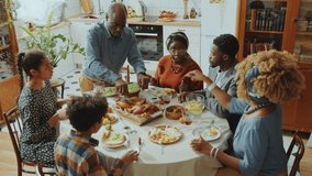 Black grandfather cutting roasted chicken and serving food on plates while taking care of family on holiday dinner at home. High angle shot - Powered by Shutterstock - Get 15% off with code: PIKWIZARD15