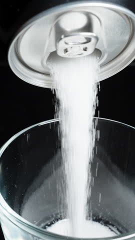 Vertical video. Sugar is poured from a can instead of soda, the concept of harmful drinks with high sugar content. Tilt, on a black background, slow-motion.
