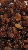 Vertical video. Raisins fall down, top view, in slow motion.