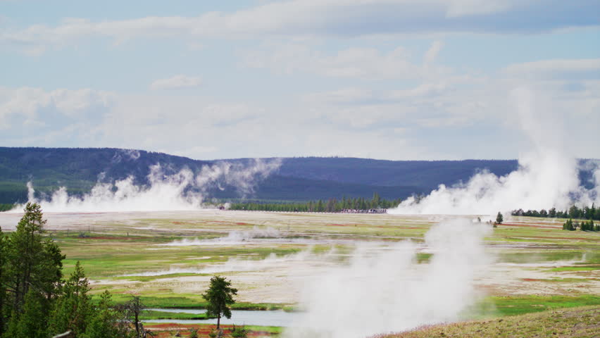 Beautiful landscape with green meadows and streams producing white thick mist, evergreen trees and dark lonely hills under blue skies with fluffy clouds, Wyoming. High quality 4k footage