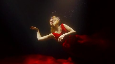 a young woman in a red wedding dress is floating under the water, she is at sea depth