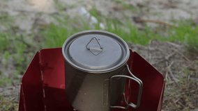 This video shows how to remove the lid from a mug of boiling water. Hot steam rises above the mug. This is an ideal shot for those who appreciate morning rituals and relaxation in nature.