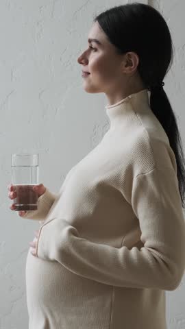 Cheerful Pregnant Woman Drinking Water From Glass At Home
