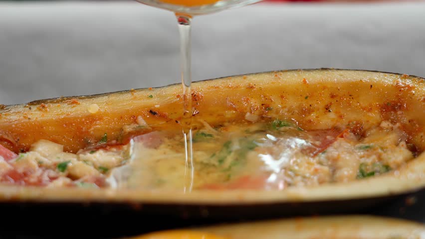 An egg is poured into boat-shaped eggplants with bacon and cheese, on a wooden board with vegetables. Macro, camera moves smoothly. Vegetarian food, vegetables, quick snack, eggplant dishes.