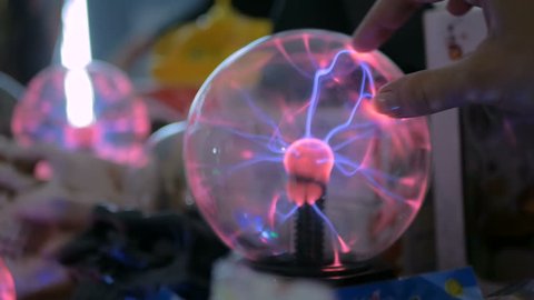Woman hand touching plasma ball at technology exhibition. Physics concept