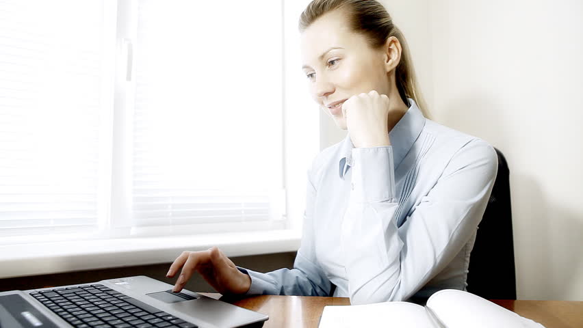 Businesswoman sitting on the desk and working with laptop