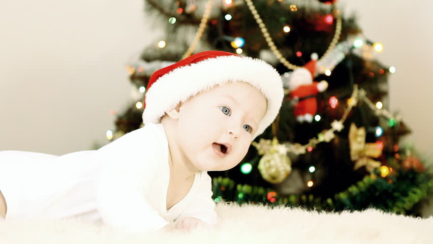 Baby in Christmas hat with christmas tree background