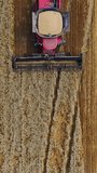 Top view of a combine harvester at work. View from above on a red agricultural machine in the field. Aerial view. Slow motion. Vertical video