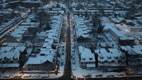 Twilight over snow-blanketed American city street, lined with row houses and lit by warm glows. Aerial reverse dolly in quaint neighborhood suburb. - Powered by Shutterstock - Get 15% off with code: PIKWIZARD15