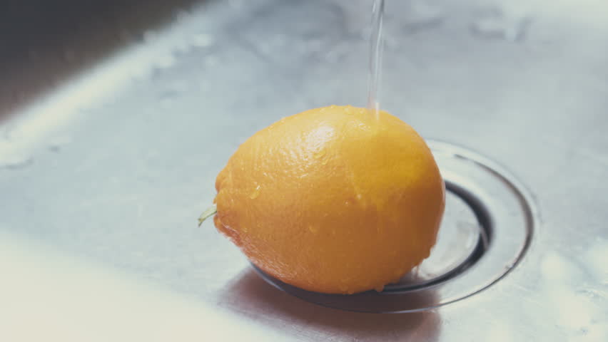 Woman washing fresh lemon, removing germs and pesticide residues from lemon skin with hot water. High quality 4k footage Royalty-Free Stock Footage #3483350079