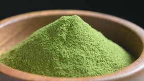 rotating Organic Green Matcha Tea powder in wood spoon 