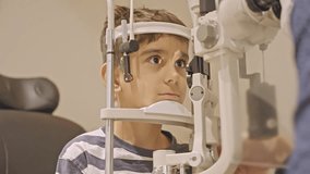Little boy's eye examination at optometrist ophthalmologist using phoropter close up. Doctor hands puts phoropter close to eyes of teen boy - Powered by Shutterstock - Get 15% off with code: PIKWIZARD15