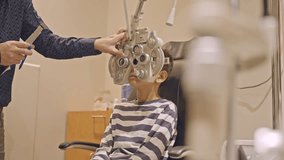 Little boy's eye examination at optometrist ophthalmologist using phoropter close up. Doctor hands puts phoropter close to eyes of teen boy - Powered by Shutterstock - Get 15% off with code: PIKWIZARD15