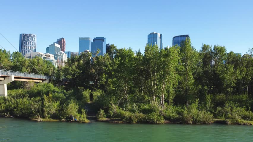 Downtown Calgary, Alberta, Canada skyline. Wide aerial drone view, from the Bow River on a sunny blue skies day. Prince Island Park.