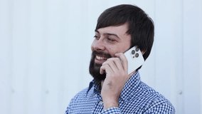 Man positive smiling beard talks phone street actively nods his head on the street. Use of smartphone technology. Communication with colleagues or family. On a white background mockup