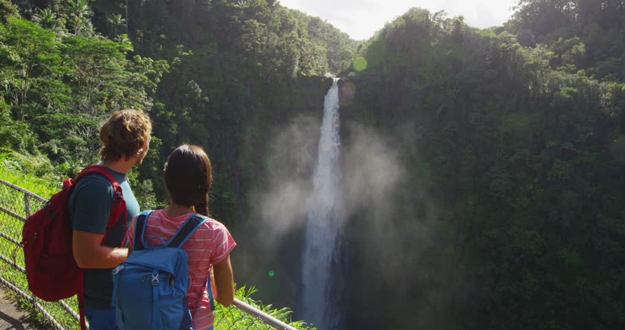 Hawaii Couple tourists on Hawaii by famous hawaiian waterfall on Big Island. Tourist girl pointing at Akaka Falls waterfall on Hawaii, Big Island, USA. Travel tourism young people concept