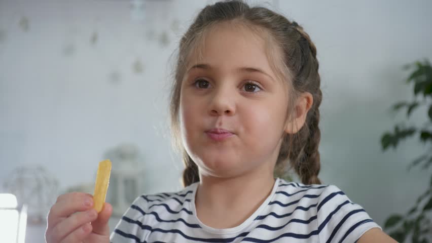 Happy family concept.child is sitting at the table at home. baby eats French fries from a box with his hands. baby