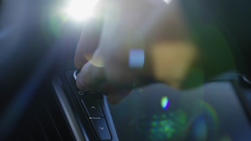 Auto technology concept.close-up of hands turning volume button of car radio.woman driving car.girl turns up volume of the music. acoustics in the car. car audio system. listen to music while driving