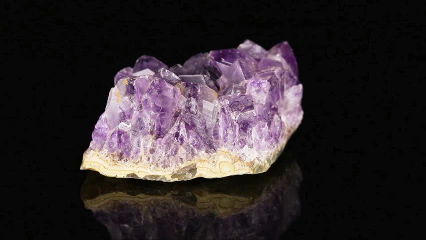 Polished mineral stone Amethyst rotates in a circle on a black background close-up