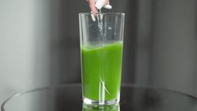 A slender hand holds a spoon in a glass full of rich, green vegetable juice - Powered by Shutterstock - Get 15% off with code: PIKWIZARD15