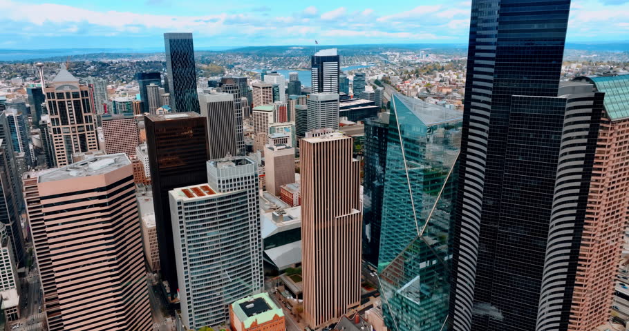 Drone going up along the stunning skyscrapers in the American downtown. Vast city view of Seattle, Washington, the USA from top at daytime.